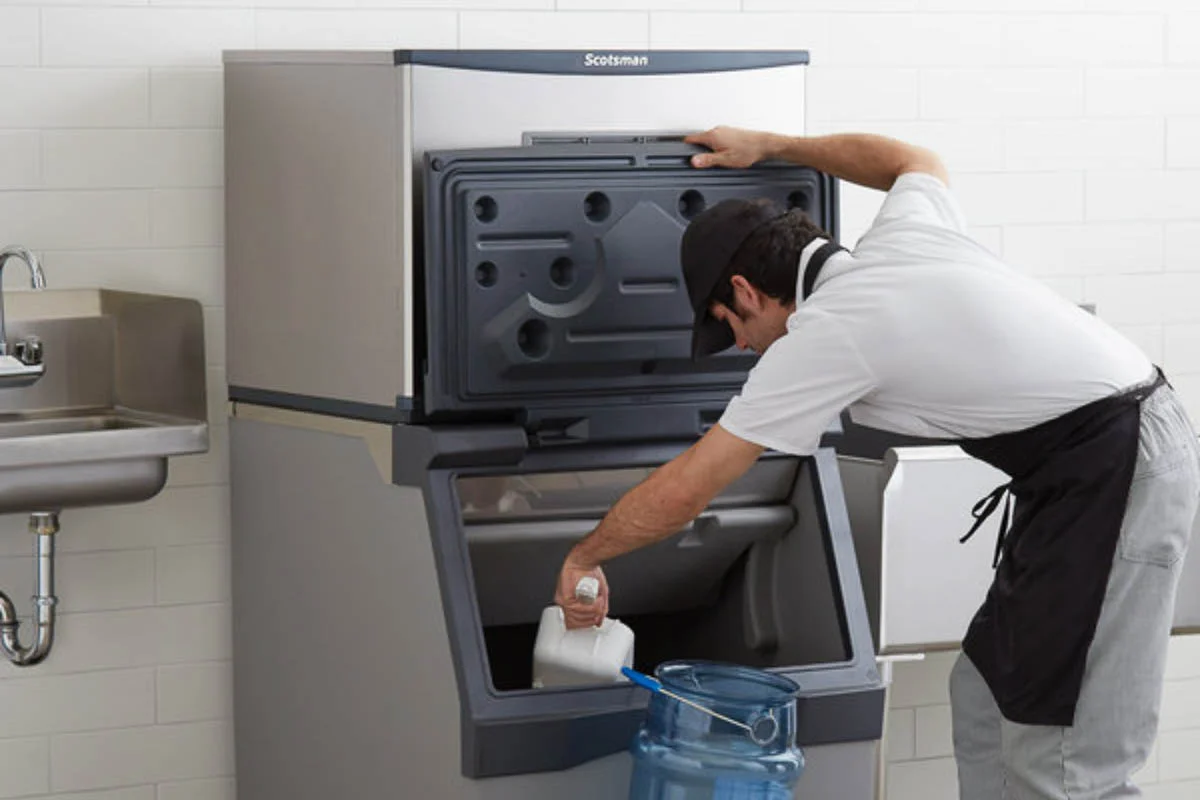 Technician servicing a standalone modular ice machine with the storage bin open