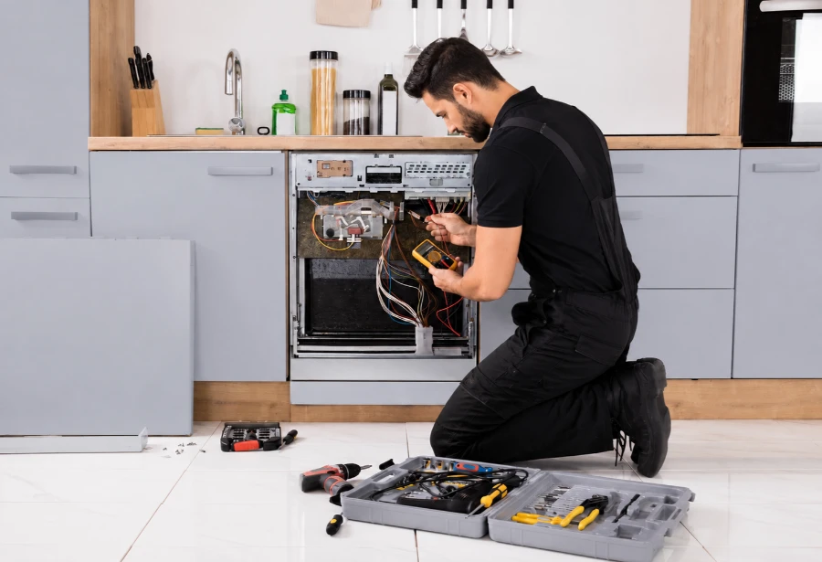 Dishwasher repair technician testing the control board wiring of an opened built-in dishwasher with a multimeter in an Austin, TX kitchen